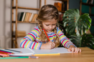 A child working on their handwriting development with colored pencils