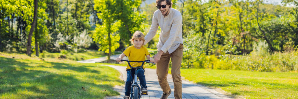 Parent teaching their son how to ride a bike