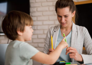 Therapist prompting child to write by holding a pencil